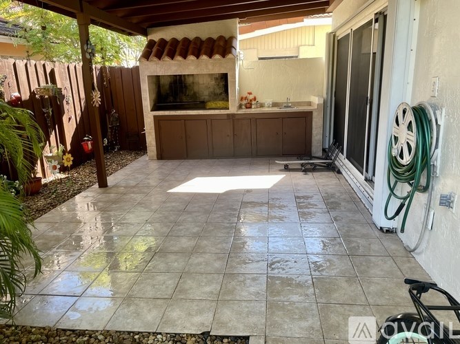 A patio with a tile floor and a hose on the wall.
