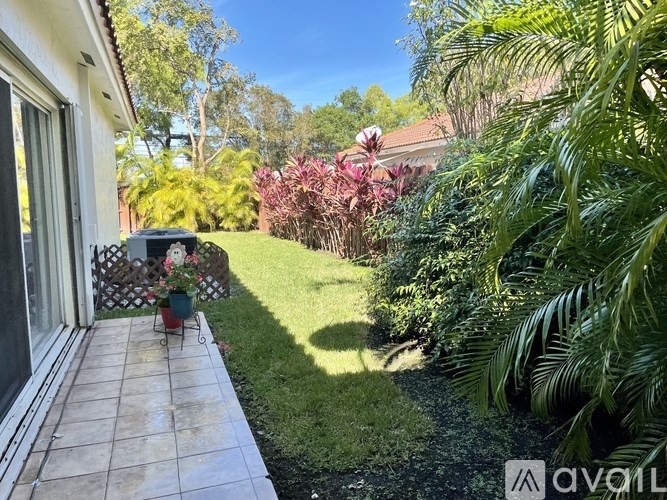A patio area with a tiled floor and a variety of plants and trees.