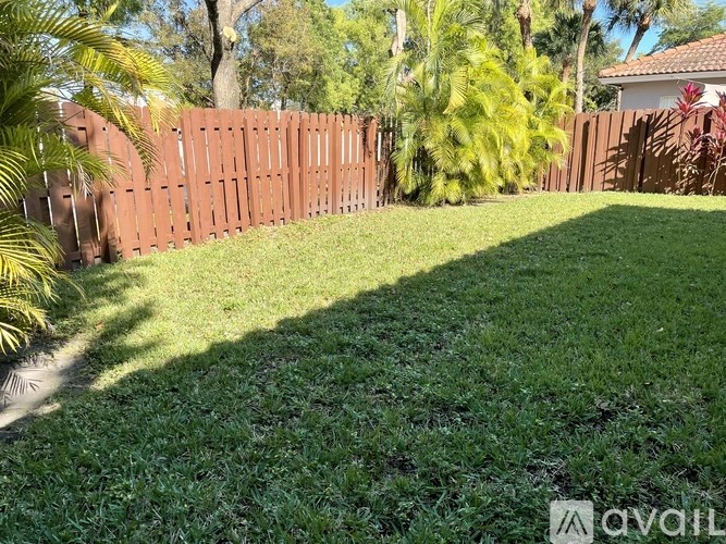 A backyard with a brown fence and green grass.