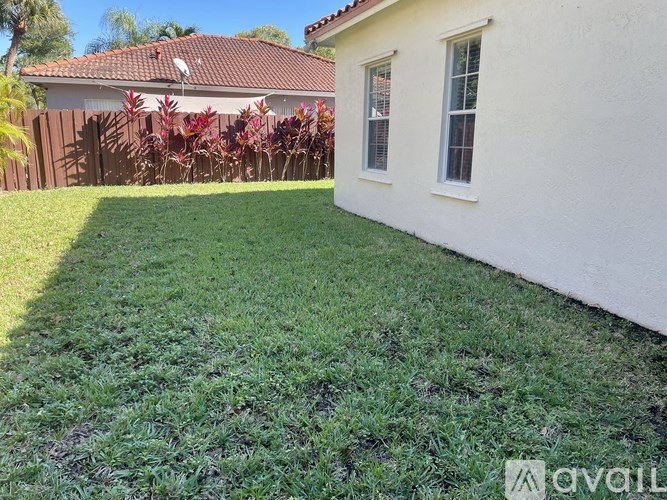 A white house with a red roof and a green lawn in front.