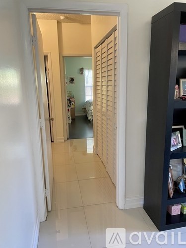 A hallway with a white door and a black bookshelf.
