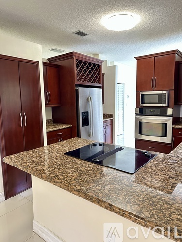 A kitchen with brown cabinets and a granite countertop.