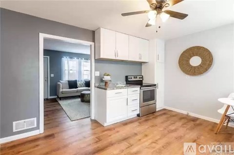 A kitchen with white cabinets and a wooden floor.