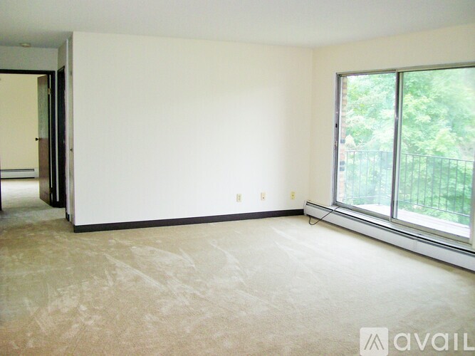 A room with a carpeted floor and a window overlooking a fence.
