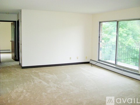 A room with a carpeted floor and a window overlooking a fence.