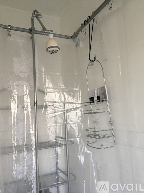 A shower with a glass door and a hanging shower caddy.