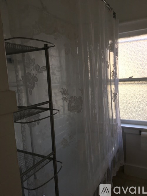 A room with a shelf and a window with curtains.