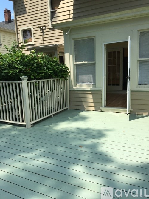 A wooden deck with a white fence and a house in the background.