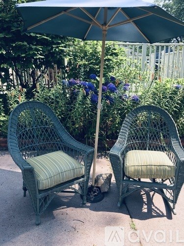 Two green chairs with striped cushions are placed under a green umbrella.