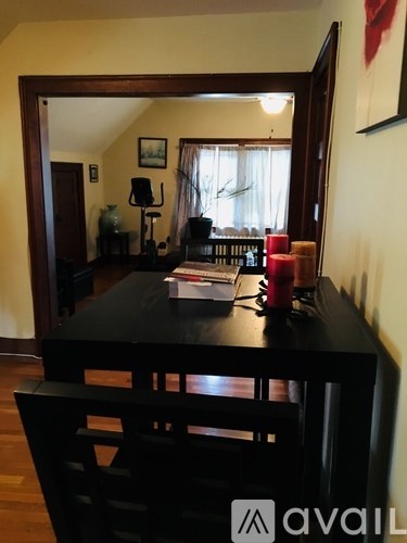 A black dining table with a mirror above it and a red candle on the table.