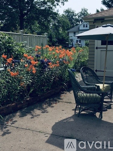 A patio with a chair and a table with a white umbrella.