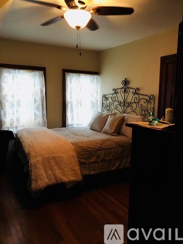 A bedroom with a bed, a ceiling fan, and a nightstand.