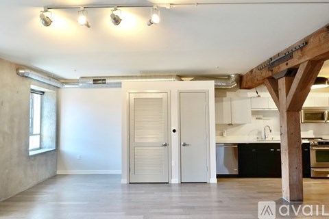 A kitchen area with a white door and a wooden beam overhead.