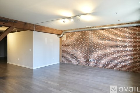 A room with a wooden beam on the ceiling and a brick wall.
