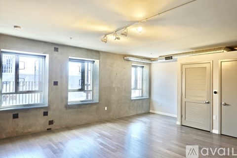 A large empty room with wooden floors and two windows.