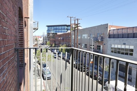A view from a balcony looking down a street lined with parked cars.
