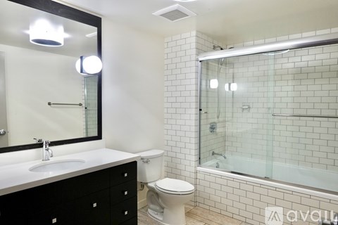A bathroom with a white sink, black cabinet, and a white toilet.