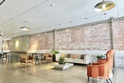 A living room with a white couch and a brick wall.