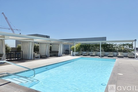 A large swimming pool with a glass barrier and a white building in the background.