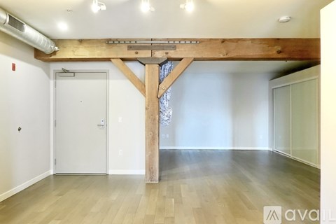 A room with a wooden beam and hardwood floors.