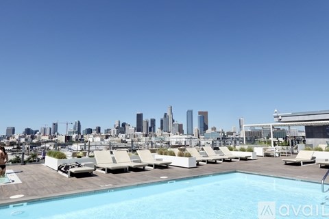 A pool with lounge chairs and a city skyline in the background.