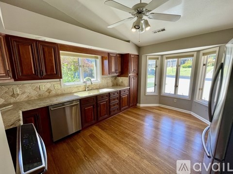 A kitchen with wooden cabinets and a stainless steel dishwasher.
