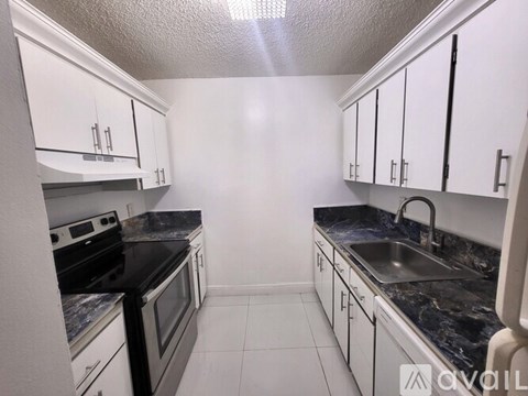 A kitchen with white cabinets and black countertops.
