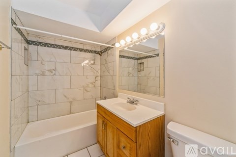 A bathroom with a marble tile shower and a white bathtub.