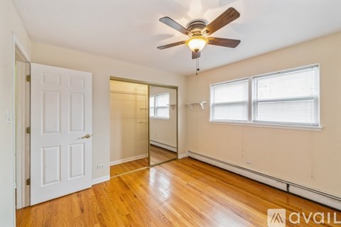 A room with a ceiling fan and wooden floors.