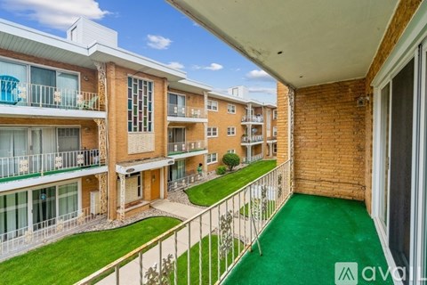 A balcony with a green carpet and a building in the background.