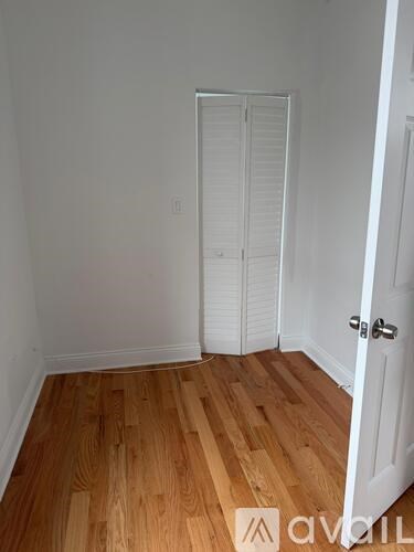 A room with a white door and wooden flooring.