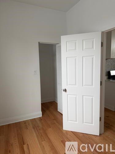 A white door is in a room with wooden floors.