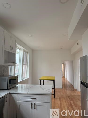A kitchen with white cabinets and a yellow stool.