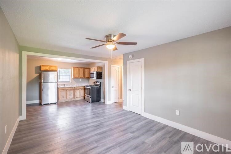 A kitchen with a refrigerator, sink, and stove is visible from the living room.
