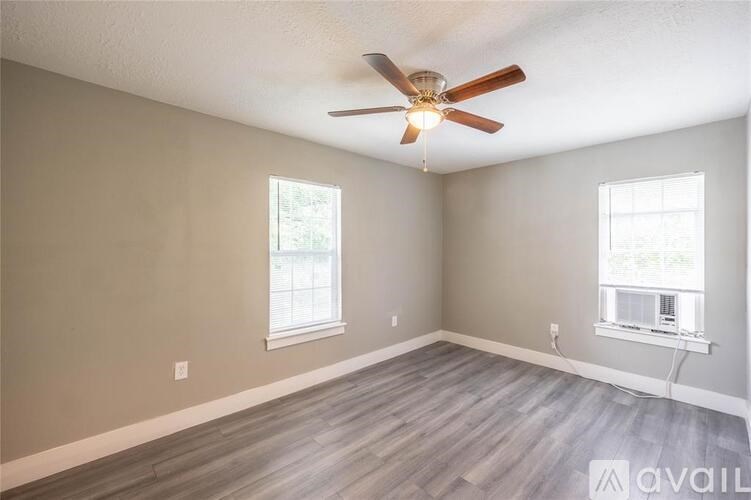 A room with a ceiling fan and two windows.