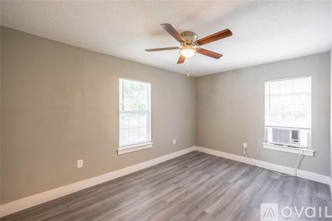 A room with a ceiling fan and two windows.