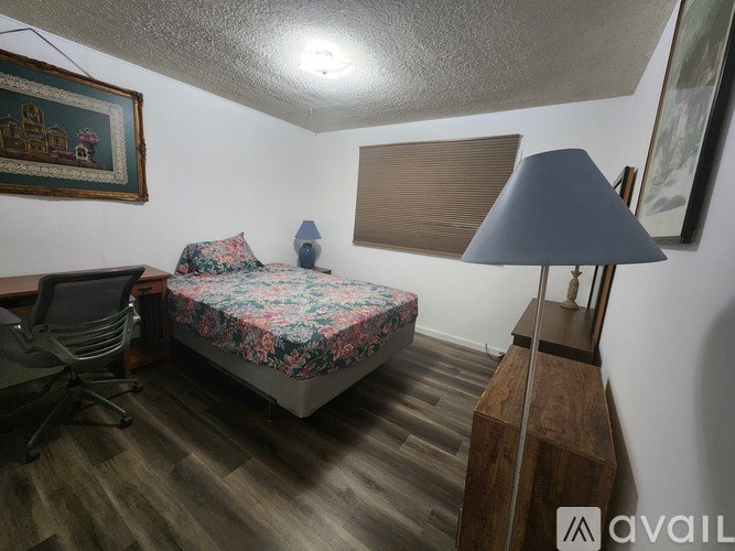 A bedroom with a bed, a chair, a desk, and a lamp.