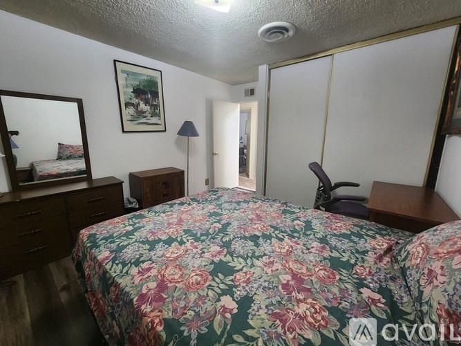 A bedroom with a floral bedspread and a mirror on the wall.
