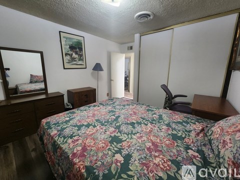 A bedroom with a floral bedspread and a mirror on the wall.