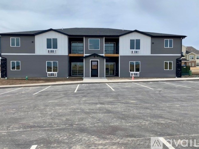 A large grey building with a parking lot in front.