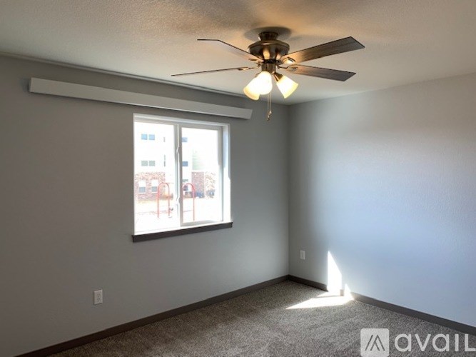 A room with a ceiling fan and a window overlooking a playground.