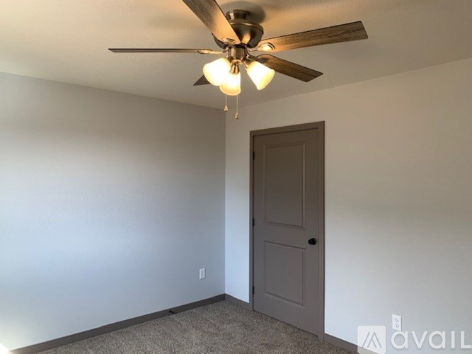 A room with a ceiling fan and a door.