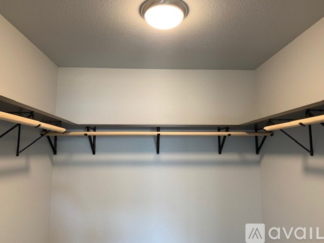A white wall with a light on the ceiling and a shelf with two rails.