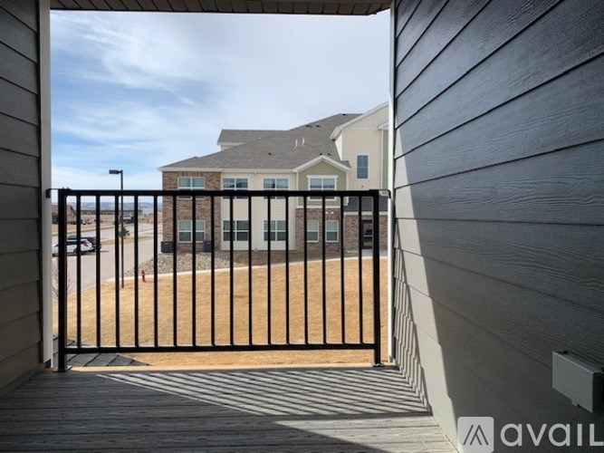 A black gate leads to a house with a brown lawn.
