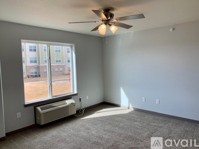 A room with a ceiling fan and a window with an air conditioner unit underneath it.