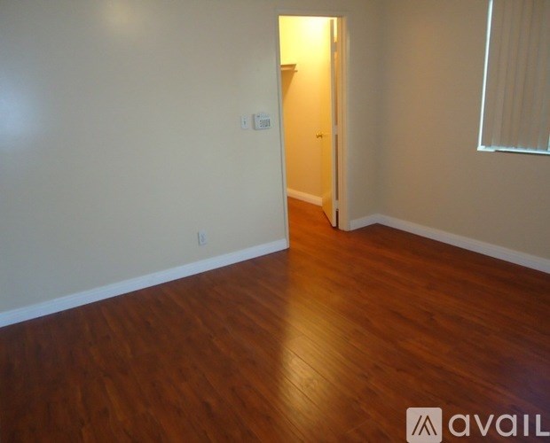 A room with wooden floors and a doorway leading to another room.
