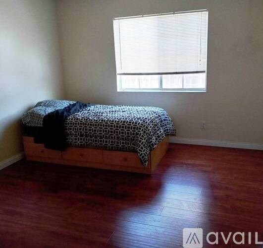 A bedroom with a bed and wooden flooring.