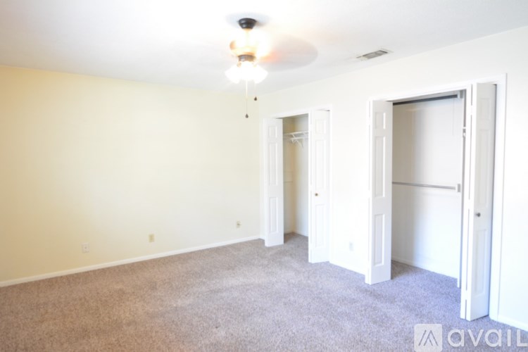 A room with a carpeted floor and a ceiling fan.