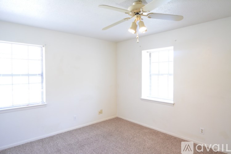 A room with a ceiling fan and two windows.