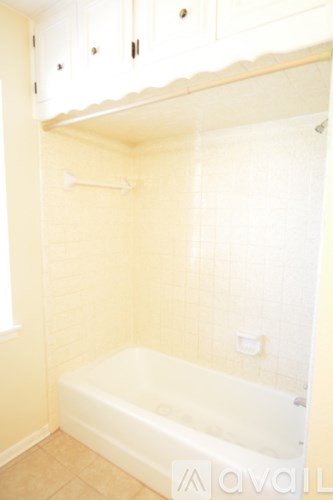 A white bathtub in a bathroom with beige walls.